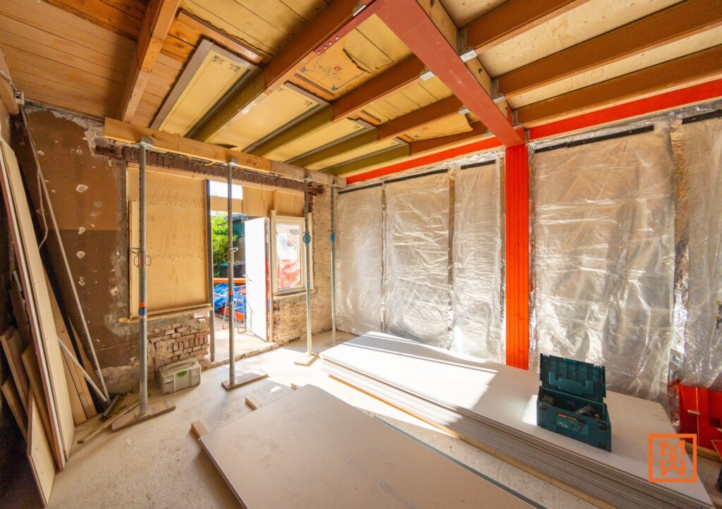 Interieur in verbouwing. Ruwe bouw met isolatie, houten balken en stutpalen. Een klusproject met bouwmaterialen en gereedschap, klaar voor de volgende fase van de huis renovatie.