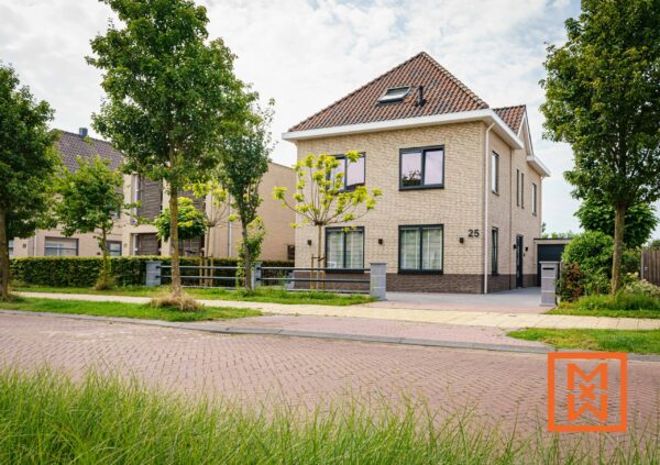 Moderne, twee verdiepingen tellende beige bakstenen woning met donkere ramen op nummer 25, gelegen in een rustige woonwijk. Weelderige groene bomen en goed onderhouden gazons omringen het pand en creëren een serene sfeer.