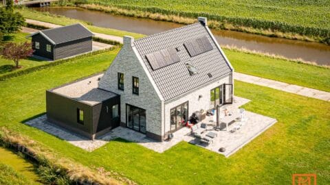 Luchtfoto van moderne boerderij met zonnepanelen en terras door Van Weenen Bouwbedrijf