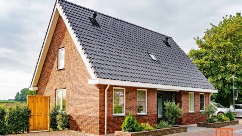 Modern bakstenen huis met donker dak, voorbeeld van hedendaags huisontwerp. door Van Weenen Bouwbedrijf