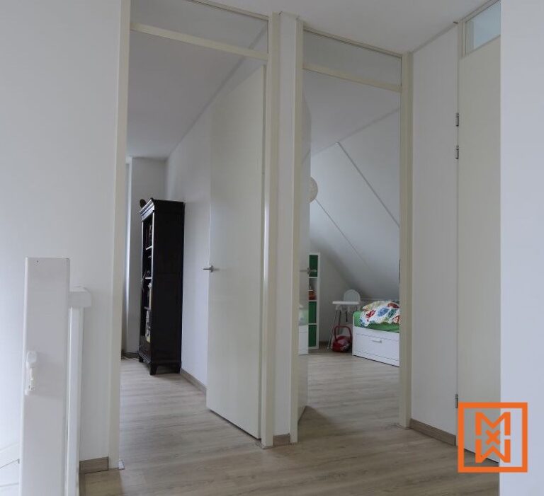 Een lichtgrijze laminaatvloer loopt door een gang met witte deuren en kozijnen, die uitkomt op een kinderkamer met een groen-wit bed en een witte ladekast. Aan het einde van de gang is een donkere boekenkast zichtbaar. De algehele stijl is minimalistisch en licht.