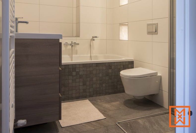 Moderne badkamer met ligbad, toilet en wastafel. door Van Weenen Bouwbedrijf