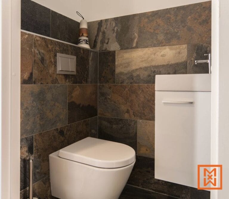 Moderne, kleine badkamer met donkere leistenen tegels, wit toilet en wastafel. door Van Weenen Bouwbedrijf