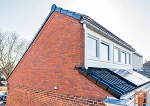 Bakstenen huis met zwart dak, dakramen en zonnepanelen. Gezien vanuit een hoek.