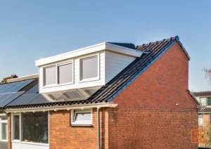 Dakkapel op bakstenen huis met zonnepanelen op het dak in Nederland.