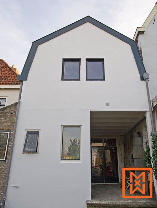 Moderne, witte uitbouw met een donkergrijs dak en strakke zwarte ramen. De gerenoveerde achterzijde beschikt over een overdekte patio en een charmante kleine tuin die zichtbaar is via een raam.