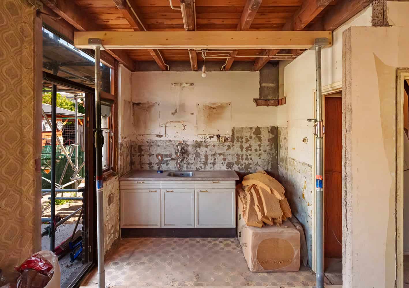 Klusproject in een oude keuken: sloopwerkzaamheden met steunpilaren, verwijderde tegels en een stapel isolatiemateriaal. Renovatie en verbouwing in huis.
