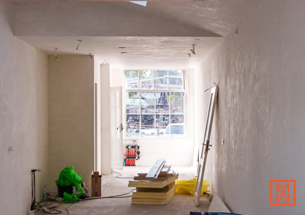 Interieur van een kamer in renovatie met gipsmuren, een raam met uitzicht op de straat, bouwmaterialen en gereedschap. Klaar voor de volgende stappen.
