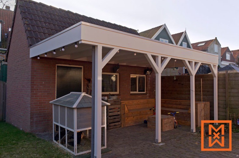 Een charmante patio in de achtertuin is voorzien van een nieuw gebouwde houten pergola met lichtsnoeren, die schaduw bieden op een stenen terras. Houten banken en een kippenhok dragen bij aan de rustieke sfeer. Het uitzicht is vredig en uitnodigend.