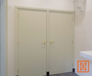 Een paar lichtgroene dubbele deuren met messing handgrepen, geplaatst in een licht betegelde badkamer. De deuren hebben een eenvoudig, modern ontwerp.