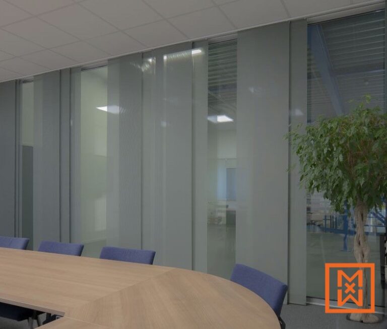 Moderne vergaderruimte met een grote lichthouten tafel en blauwe stoelen, gedeeltelijk verduisterd door strakke, grijze verticale jaloezieën die privacy en lichtregeling bieden. De jaloezieën zijn geïnstalleerd op een glazen wand en bieden uitzicht op een magazijnachtige ruimte erachter.