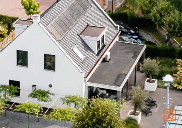 Modern huis met zonnepanelen op het dak, witte muren en een strakke, groene tuin. Een toonbeeld van duurzaam wonen.