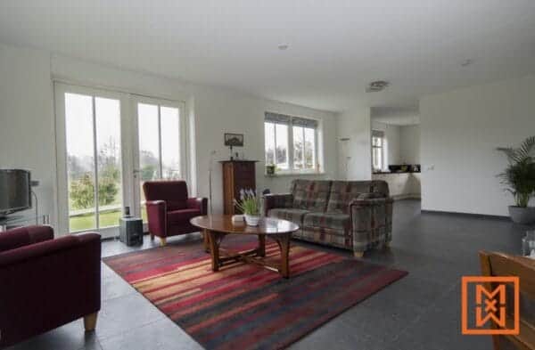 Ruime woonkamer in een vrijstaande notariswoning, met comfortabele zithoek en grote ramen. door Van Weenen Bouwbedrijf