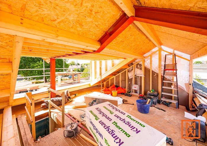 Zolderverbouwing in aanbouw met Kingspan Therma isolatie en rode stalen balken.